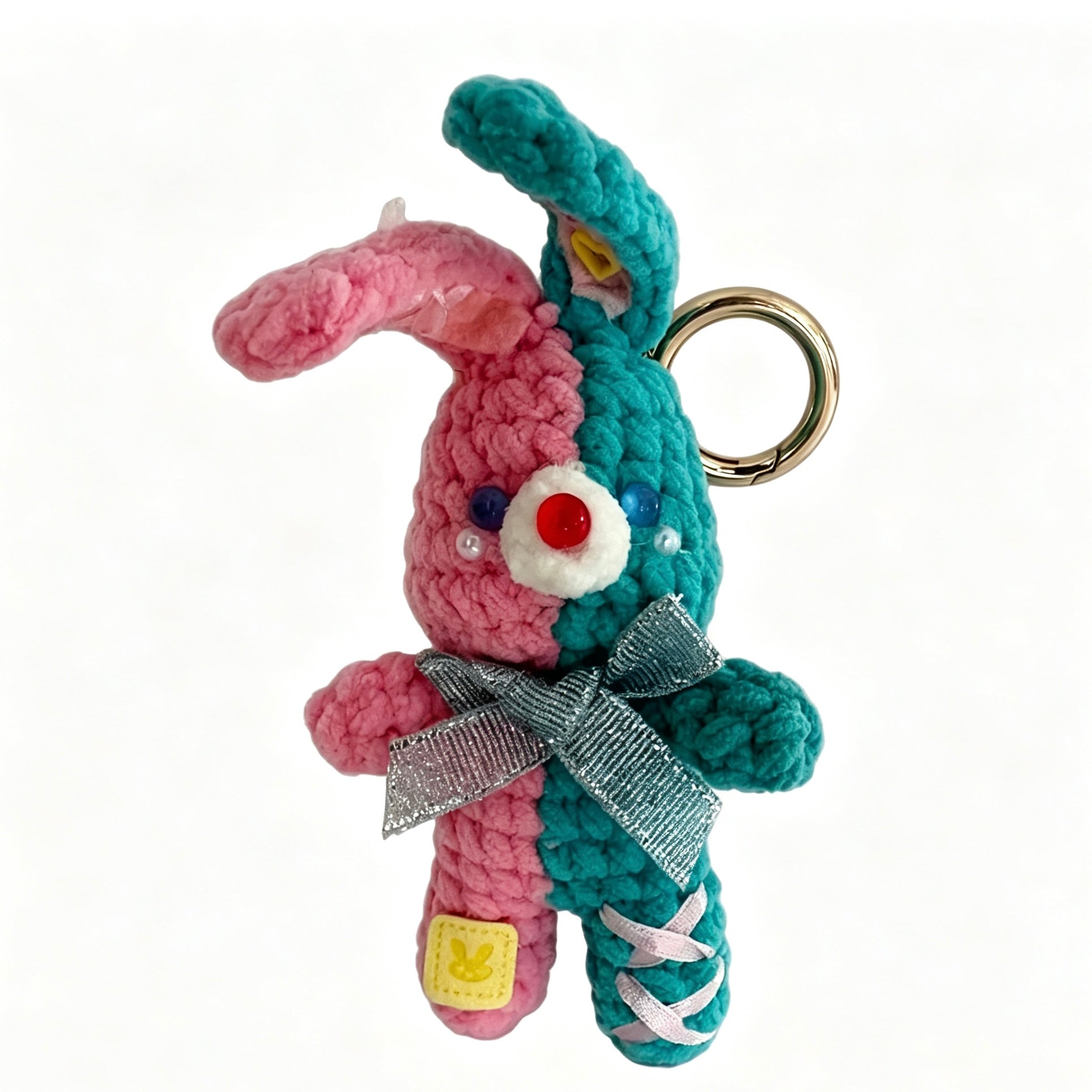 Handmade dual-color crochet bunny keychain in pink and teal with silver bow and gold ring