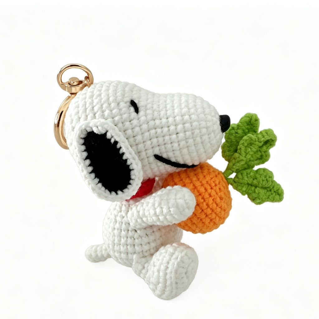 White dog amigurumi crochet keychain charm sitting and hugging a large orange carrot with green leaves, red collar, handmade
