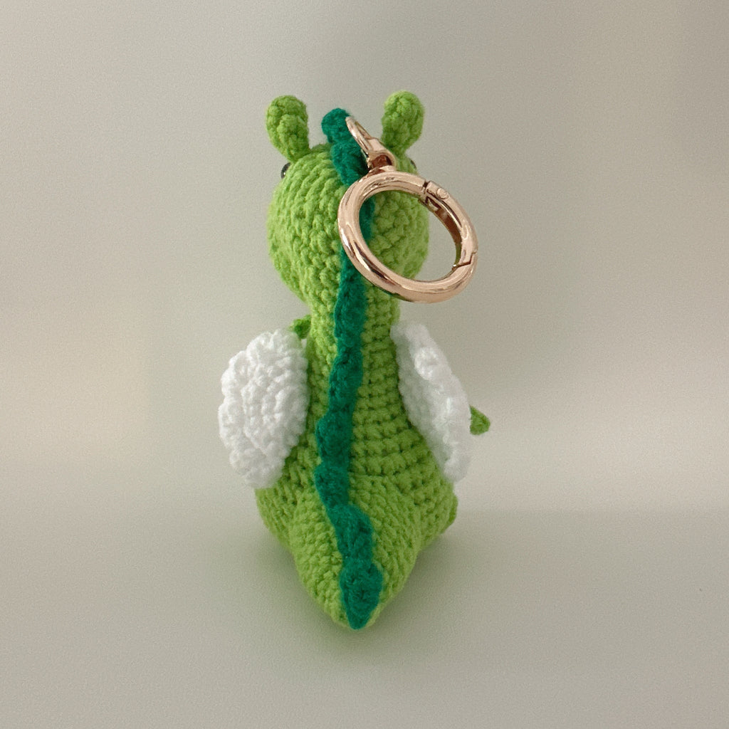 Green dragon amigurumi crochet keychain charm back view, white wings, dark green spine detail